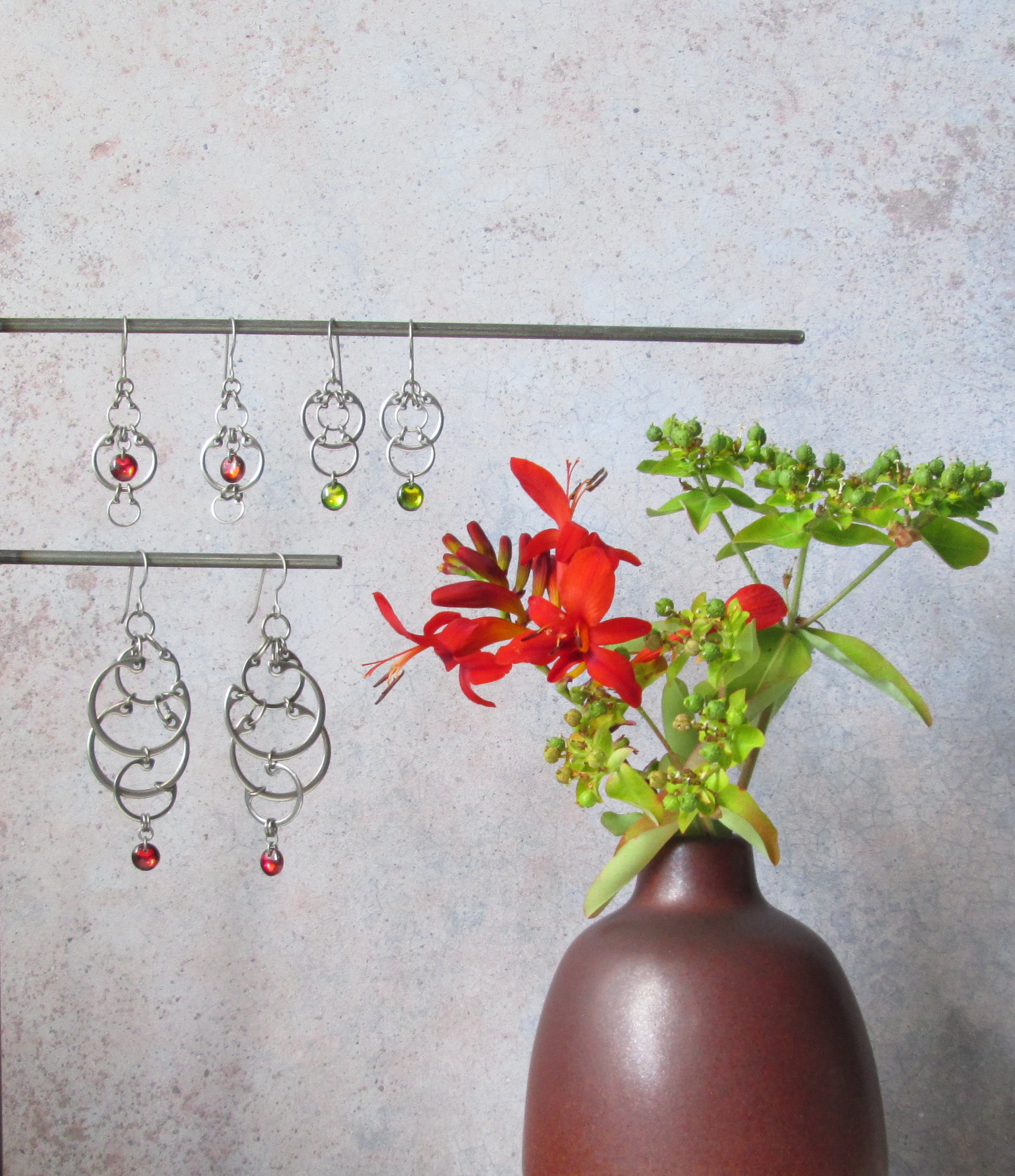 Red crocosmia flowers and green euphorbia buds with red and green earrings from Wraptillion's Industrial Glass collection.