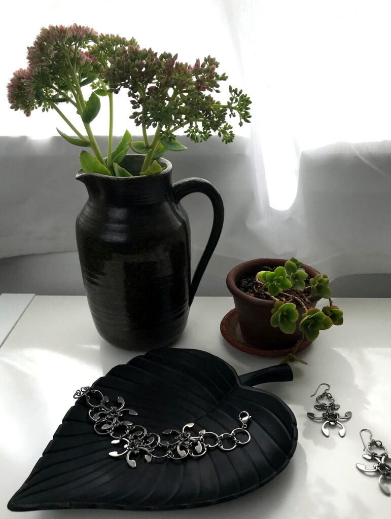 Sedum 'Autumn Joy' in a vase with a small potted sedum in Wraptillion's studio, with the Garland Bracelet and Earrings.