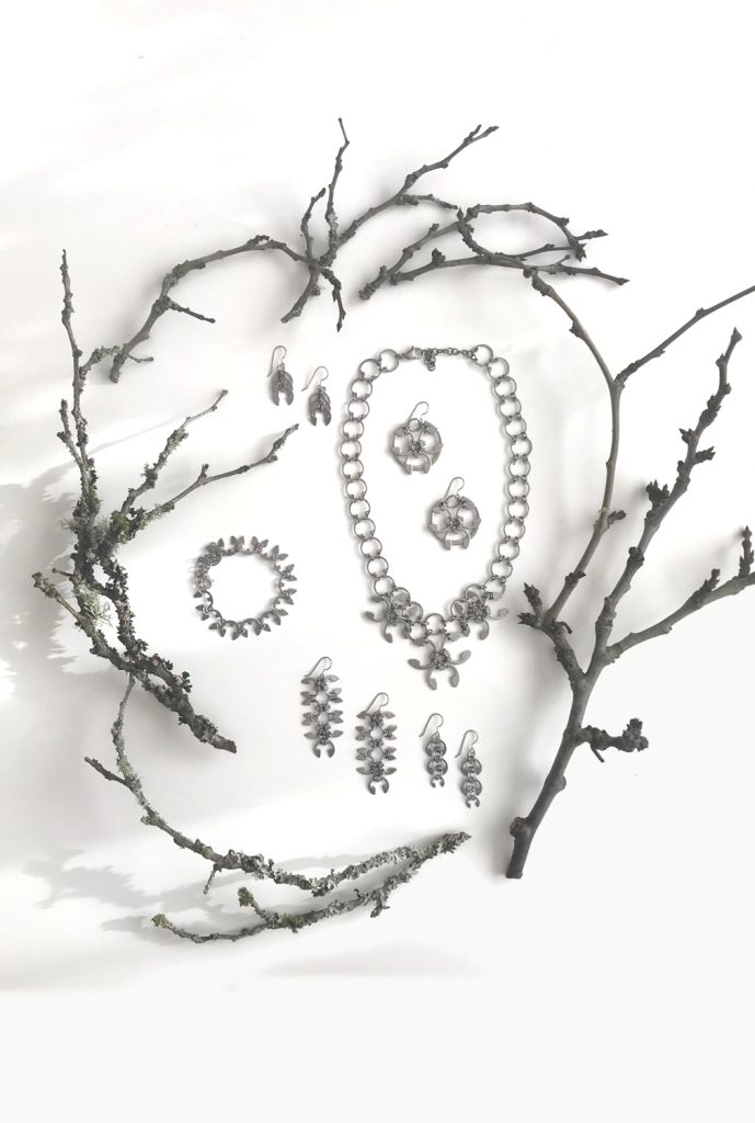 Botanical-inspired jewelry from Wraptillion's Mechanical Garden collection, surrounded by bare plum branches in winter.