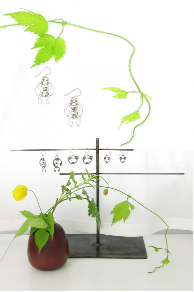 Complied image of hop vines, cut yellow Welsh poppies and hops vines in a small bud vase, and Wraptillion's Hops Earrings and Small and Large Poppies Earrings on a jewelry stand