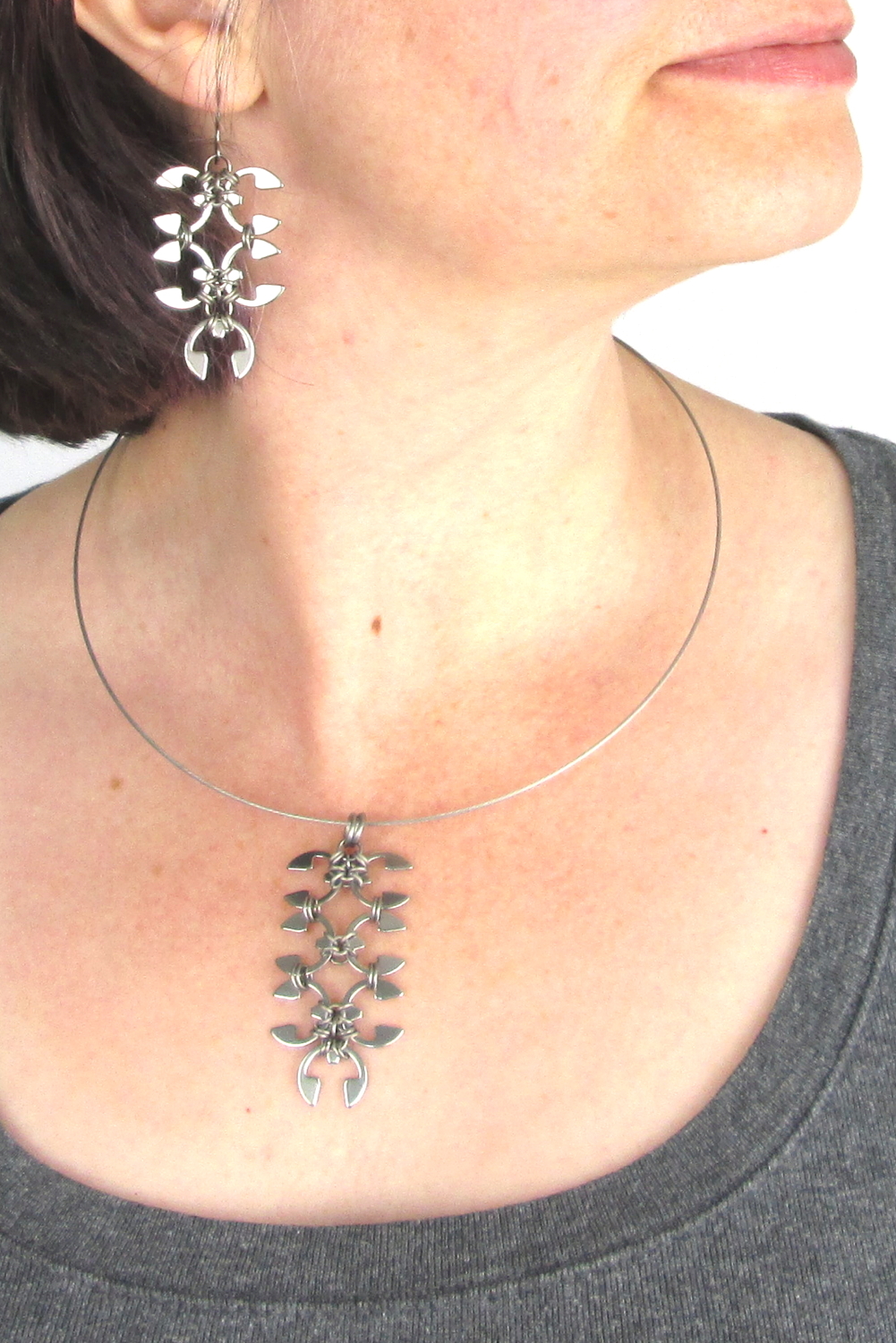 Close cropped modeled image of Wraptillion's Short Wisteria Earrings and Wisteria pendant, with a scoop neck gray tee.