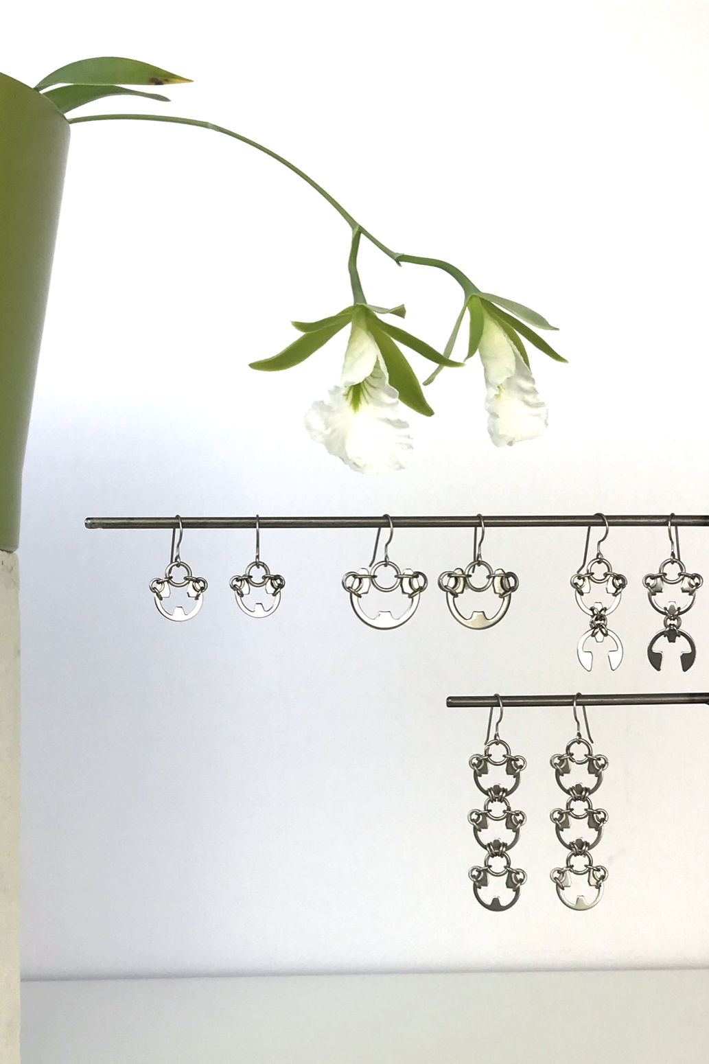 Wraptillion's Small Poppy Earrings, Large Poppy Earrings, Scarab Earrings, and Lotus Earrings with blooming orchid Encyclia mariae.