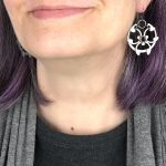 Close cropped image of a white woman with purple hair wearing spiky modern chainmail